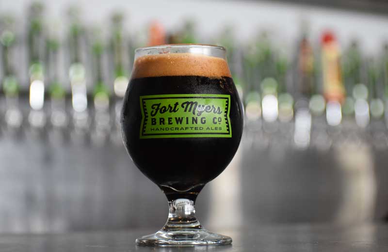 A glass of dark beer sitting on a bar.