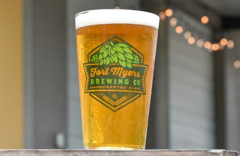 A glass of beer sitting on a wooden table.