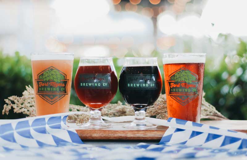 Three glasses of beer on a wooden board.