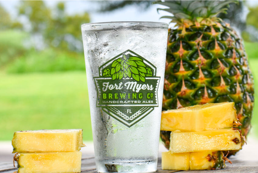 A glass of water with pineapples and a slice of pineapple.