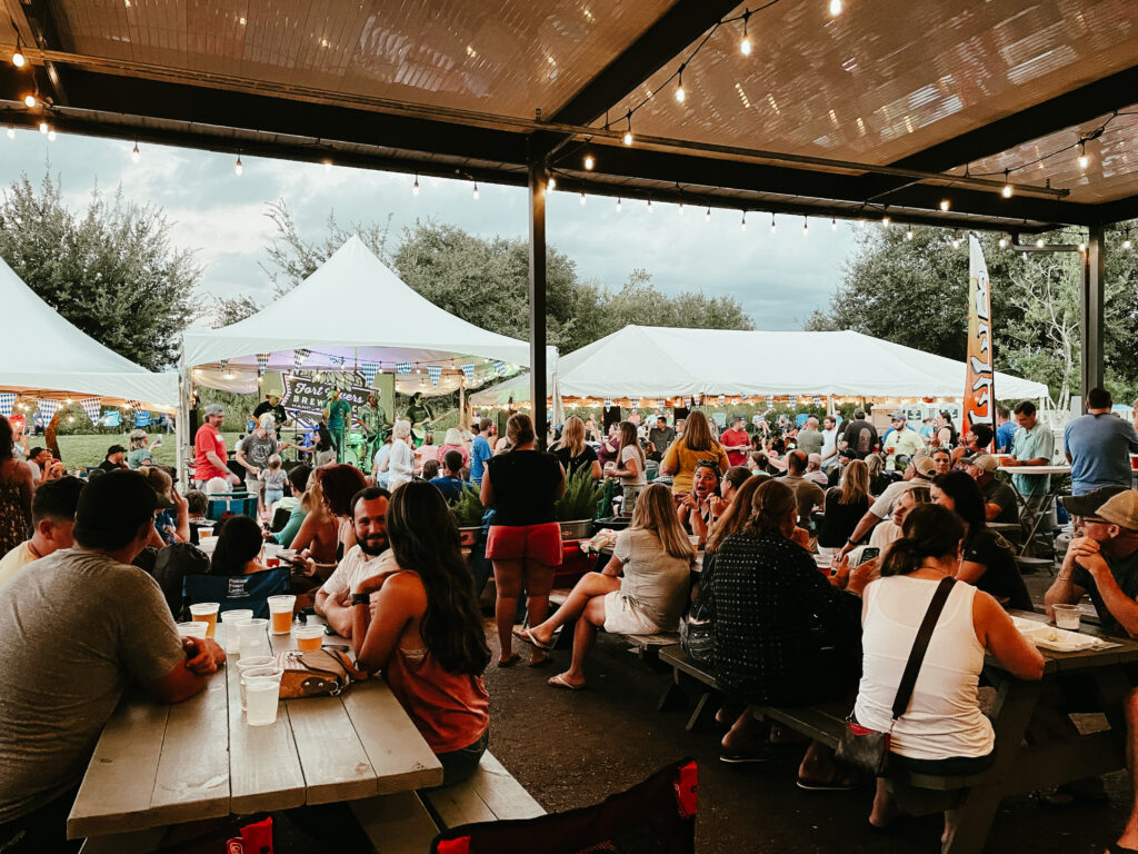 a crowd of people sitting at tables under tents.